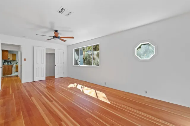 a view of an empty room with window and wooden floor