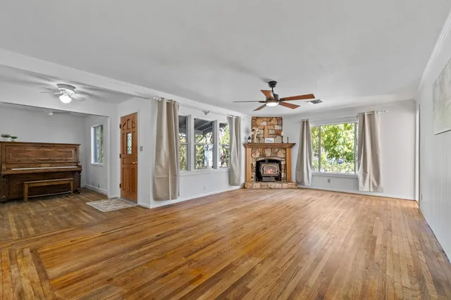 a view of an empty room with wooden floor fireplace and a window