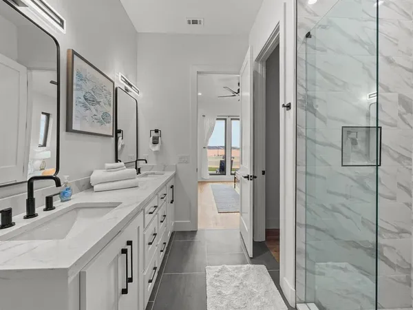 a spacious bathroom with a double vanity sink a mirror and shower