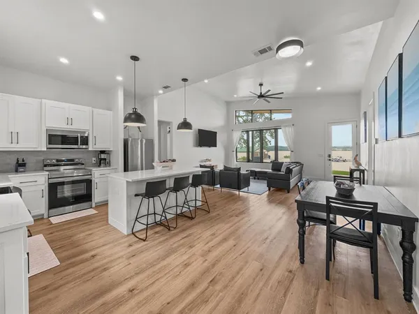 a kitchen with stainless steel appliances a dining table chairs stove refrigerator and cabinets