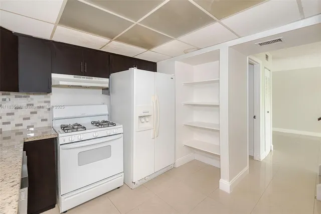 a kitchen with granite countertop white cabinets and white appliances