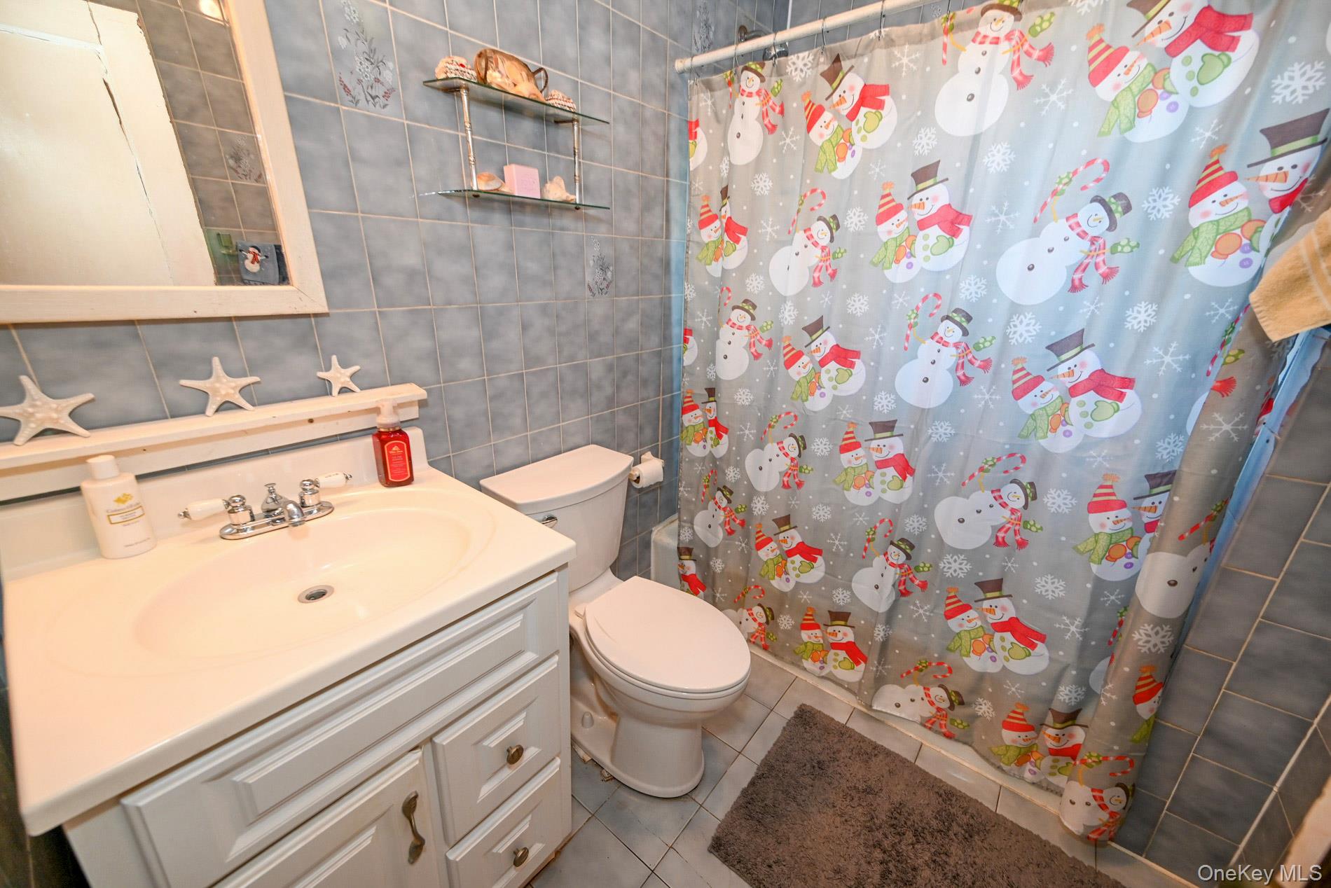 165 Cochran Place Valley Stream, NY 11581 - Photo 15 of 25 Full bath with vanity, tile walls, and light tile patterned floors