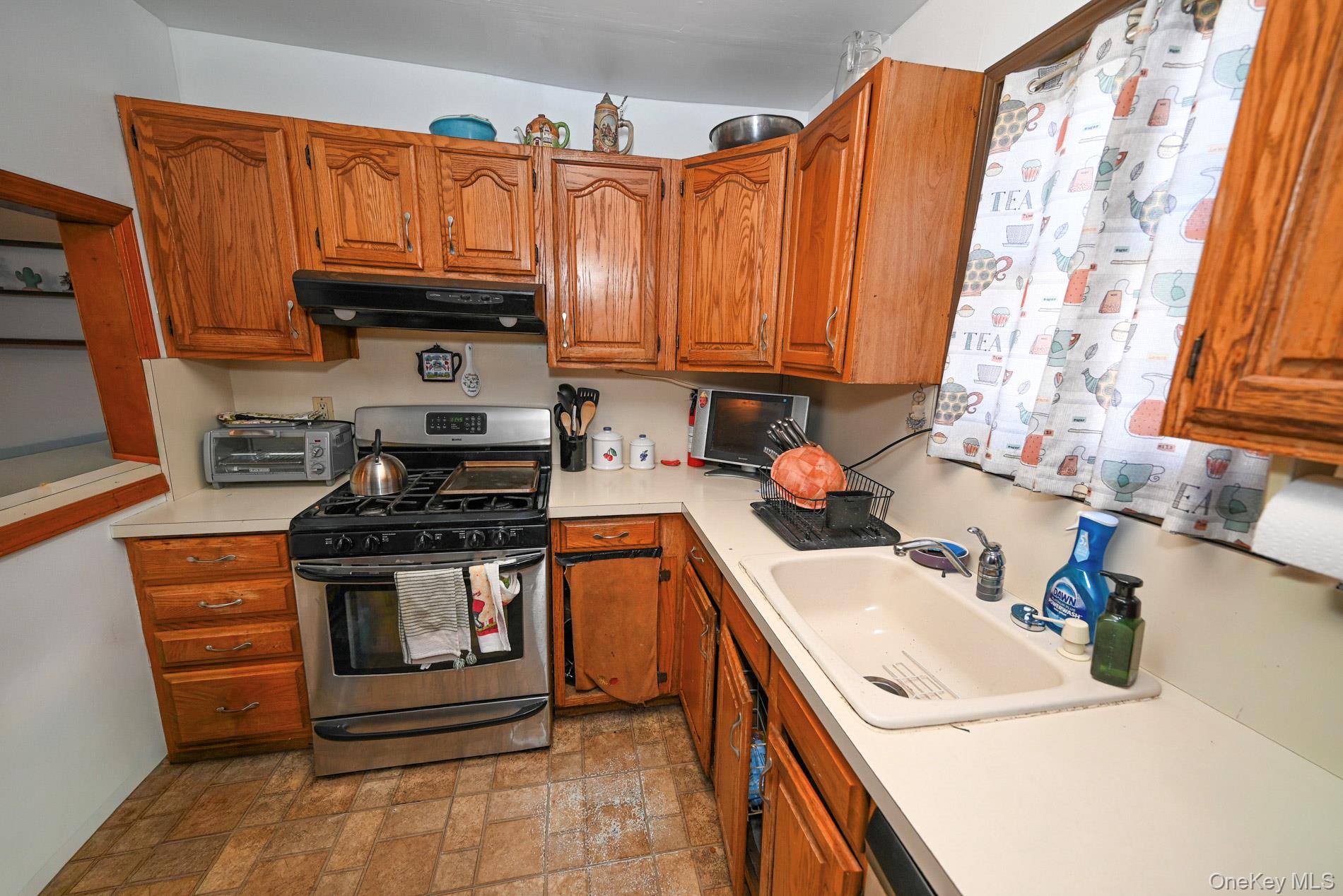 165 Cochran Place Valley Stream, NY 11581 - Photo 8 of 25 Kitchen featuring stainless steel range with gas cooktop, light countertops, brown cabinets, exhaust hood, and stone finish flooring
