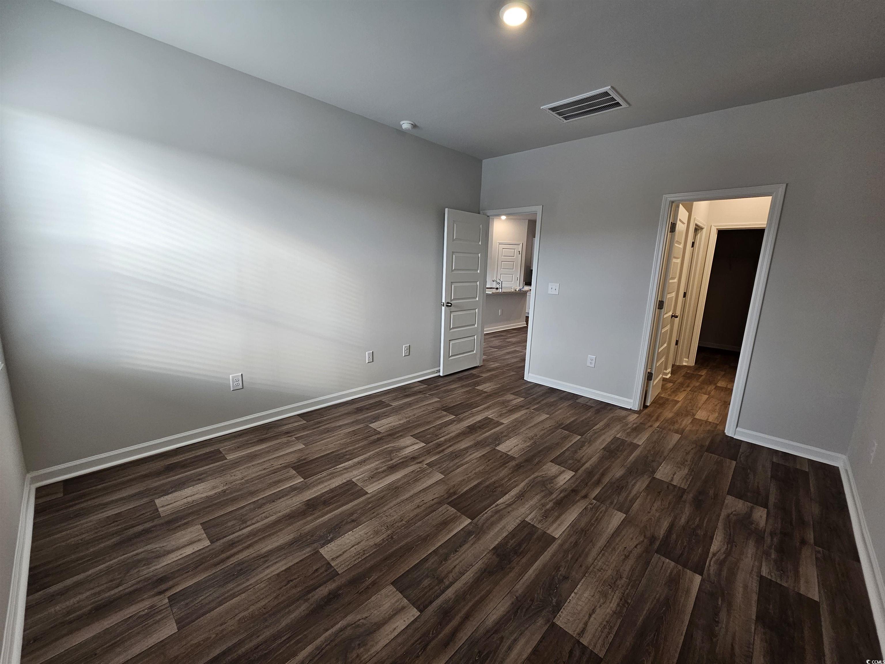 2100 Wild Indigo Circle Calabash, NC 28467 - Photo 14 of 31 Unfurnished bedroom featuring dark wood finished floors and a walk in closet