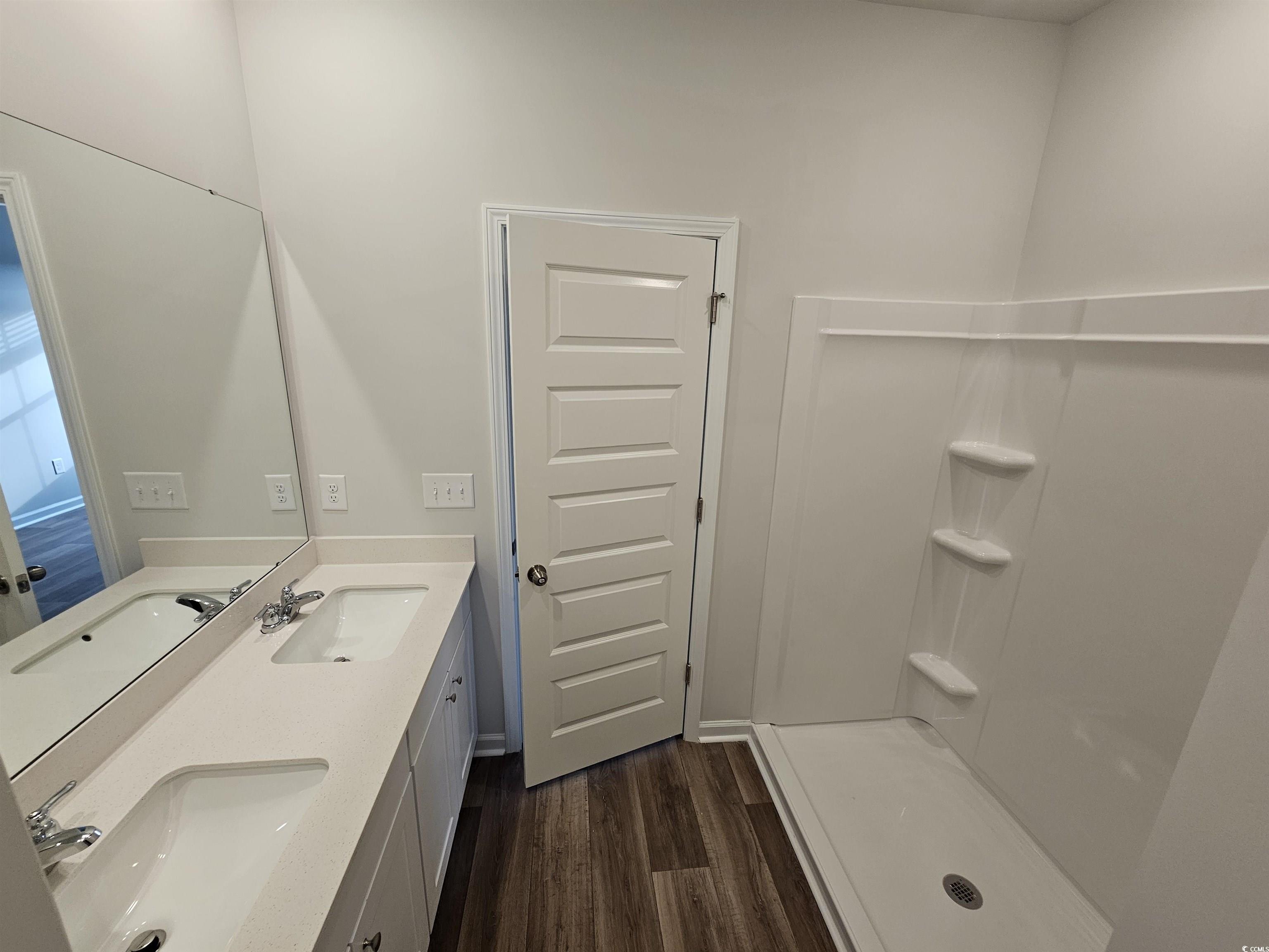2100 Wild Indigo Circle Calabash, NC 28467 - Photo 18 of 31 Bathroom with double vanity, dark wood-style floors, and a shower