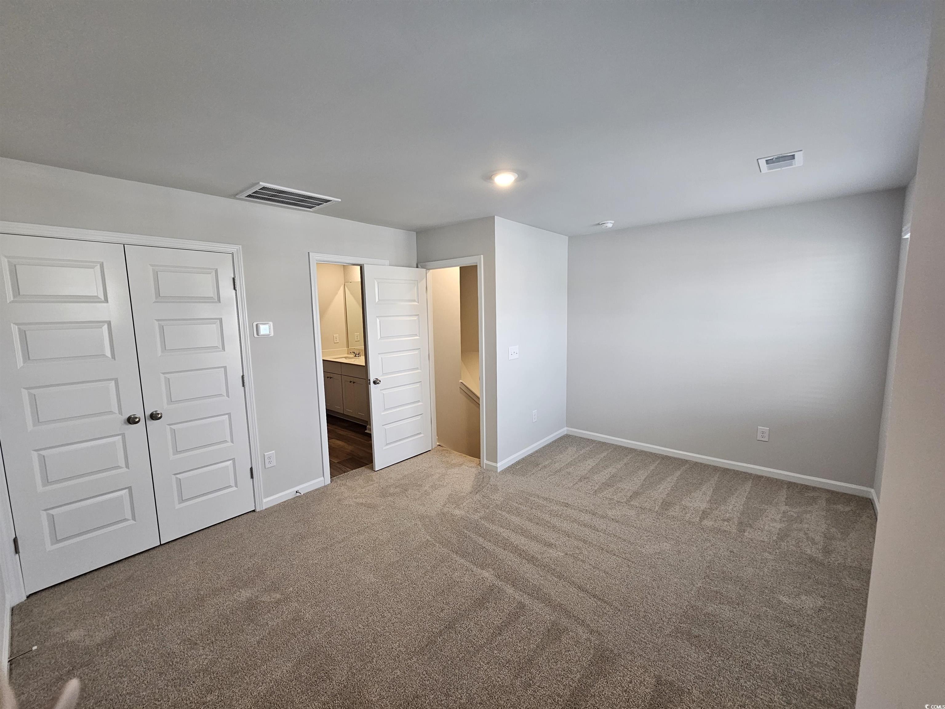 2100 Wild Indigo Circle Calabash, NC 28467 - Photo 25 of 31 Unfurnished bedroom featuring a closet, ensuite bathroom, and carpet