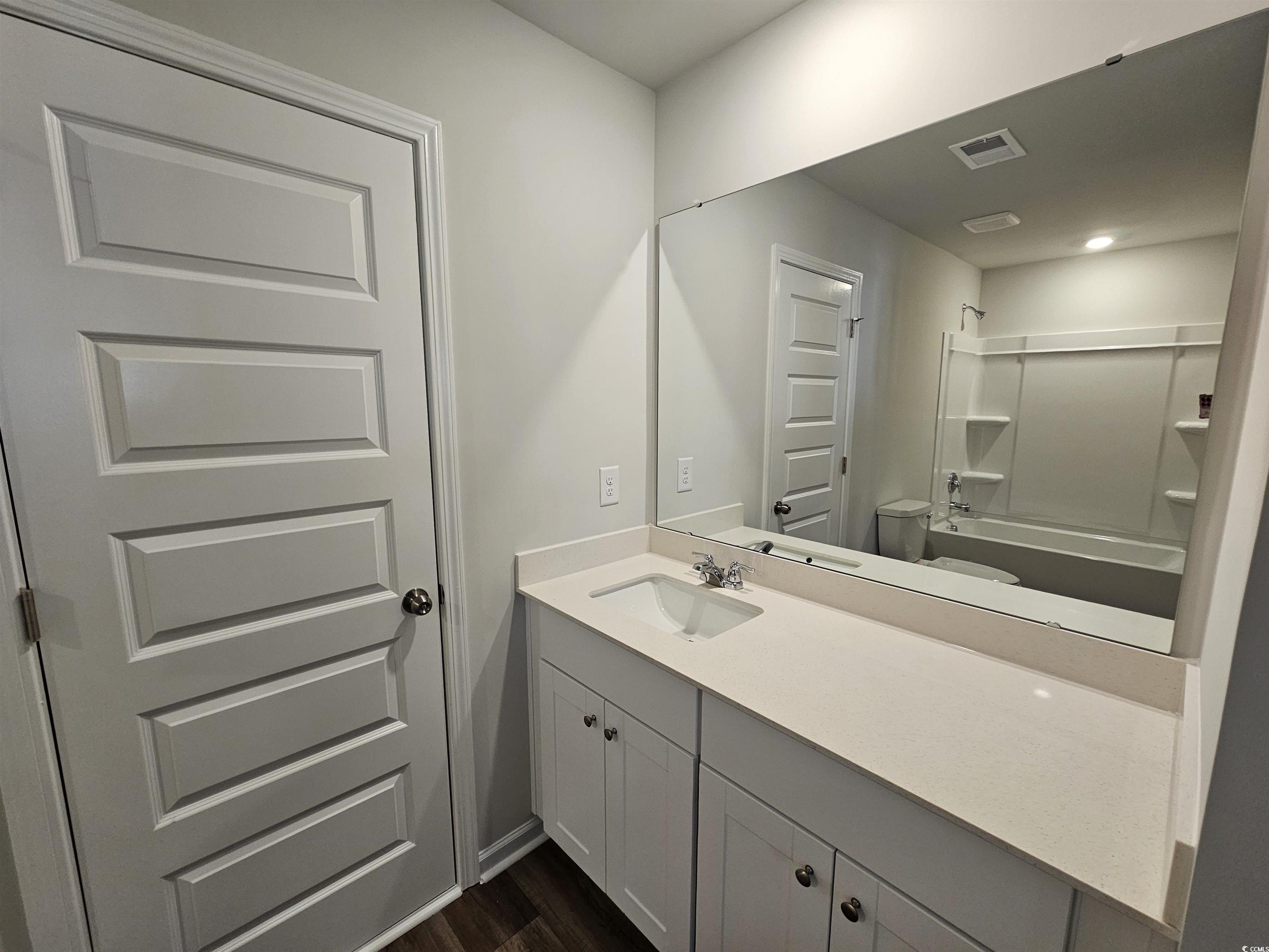 2100 Wild Indigo Circle Calabash, NC 28467 - Photo 28 of 31 Full bath featuring vanity, shower combination, and dark wood finished floors