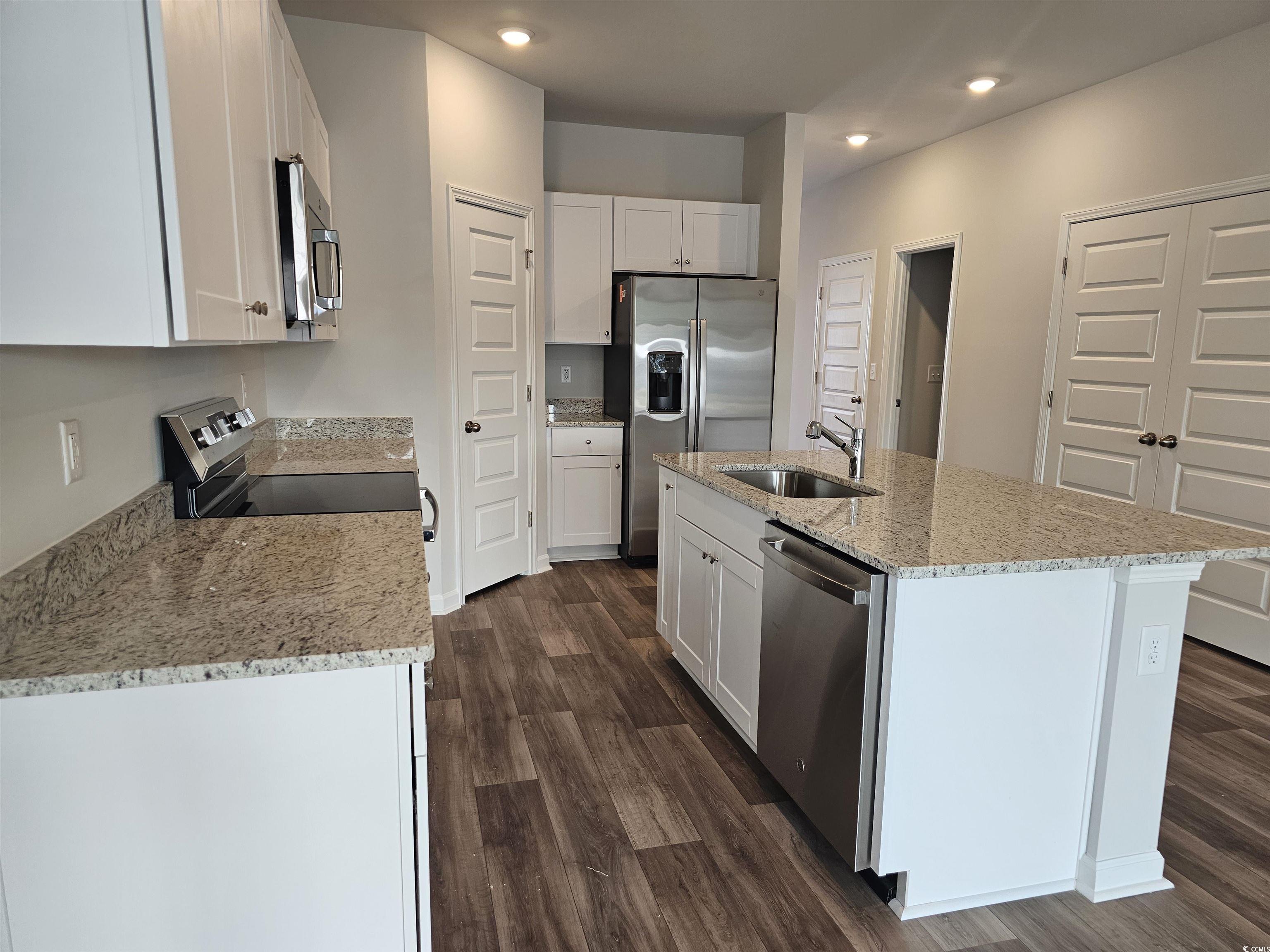 2100 Wild Indigo Circle Calabash, NC 28467 - Photo 6 of 31 Kitchen with light stone countertops, stainless steel appliances, an island with sink, white cabinetry, and recessed lighting
