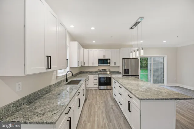 a large kitchen with granite countertop a large counter top stainless steel appliances and cabinets