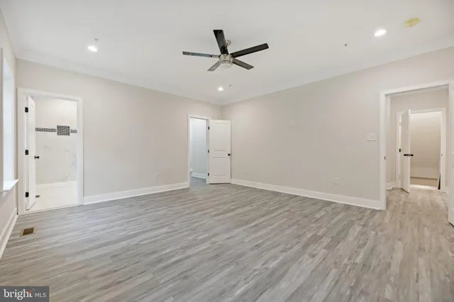an empty room with wooden floor and ceiling fan