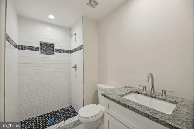 a bathroom with a granite countertop sink toilet and shower