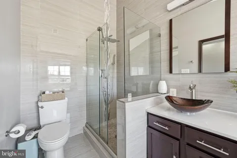 a bathroom with a granite countertop sink a toilet a mirror and shower
