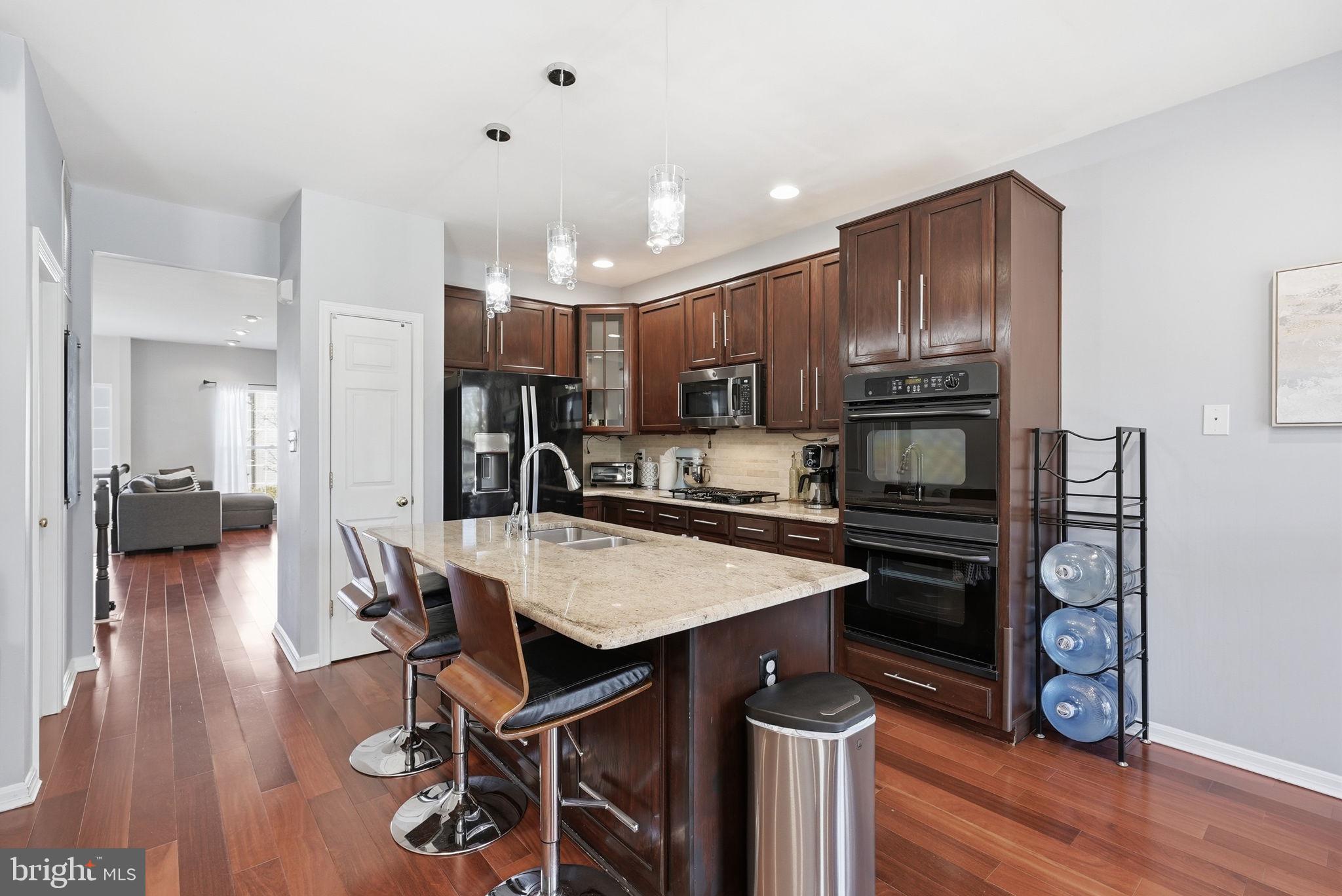 14231 Hunters Run Way Gainesville, VA 20155 - Photo 8 of 41 a kitchen with a refrigerator a stove a sink and a dining table with wooden floor