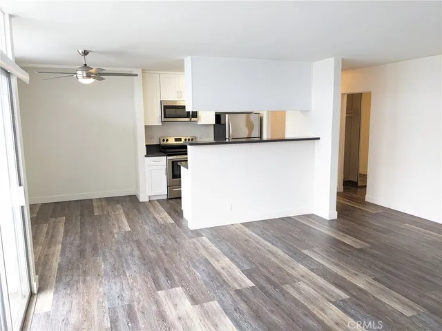a view of kitchen and empty room with wooden floor