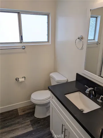 a bathroom with a granite countertop sink toilet and a window