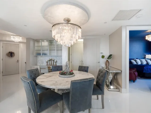 a kitchen with stainless steel appliances kitchen island granite countertop a refrigerator a stove a dining table and chairs with wooden floor