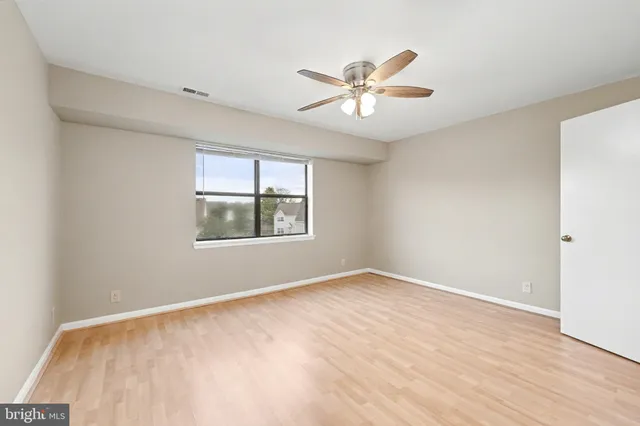 a view of an empty room with window and wooden floor