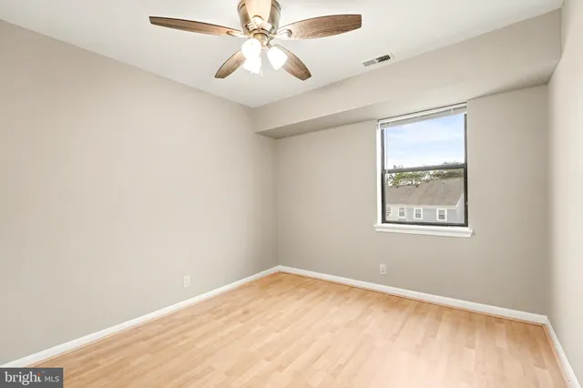 an empty room with a window and a fan