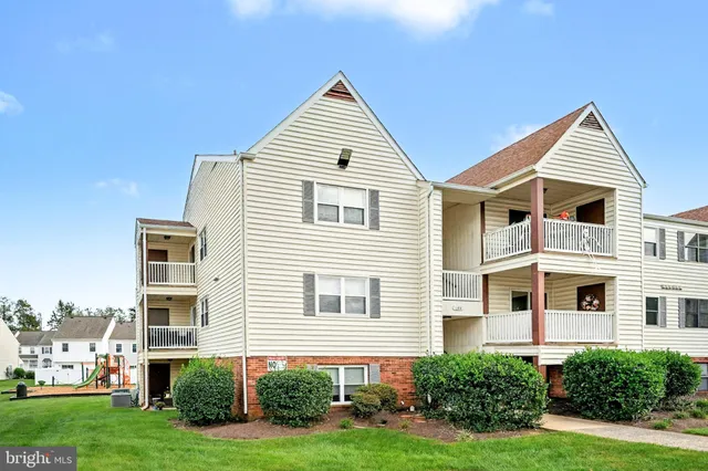 a view of a white house next to a yard with big trees