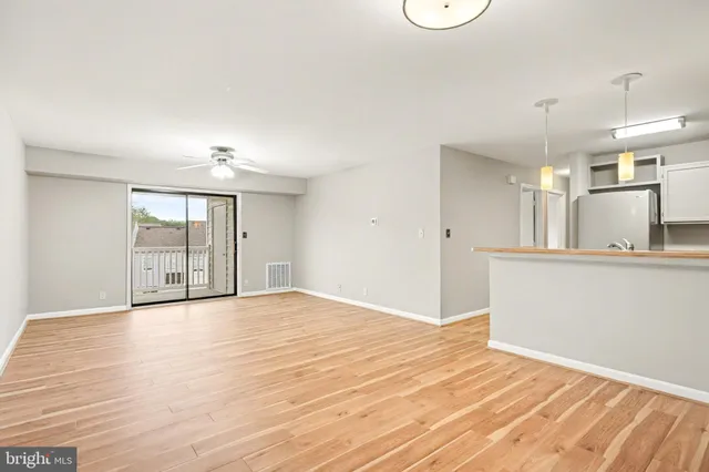a view of an empty room with window and wooden floor