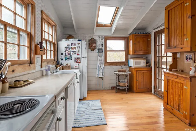 a kitchen with stainless steel appliances granite countertop a refrigerator a sink dishwasher a stove and a dining table with wooden floor