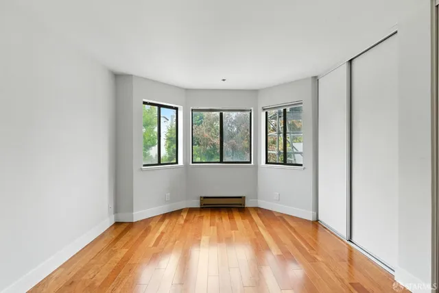 a view of empty room with wooden floor and fan