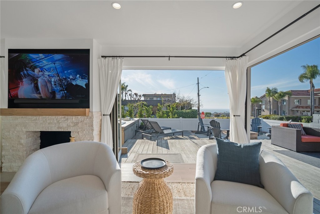 24272 Selva Road Dana Point, CA 92629 - Photo 4 of 59 a living room with furniture a fireplace and a floor to ceiling window
