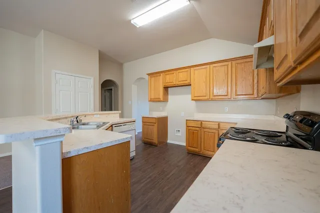 a kitchen with a sink a stove cabinets and a wooden floor