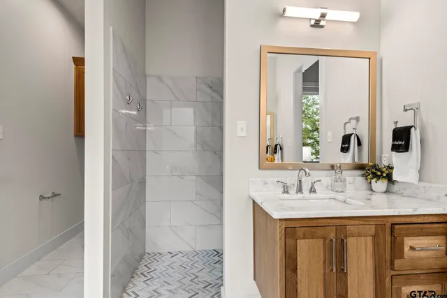 a bathroom with a granite countertop sink a mirror and a shower
