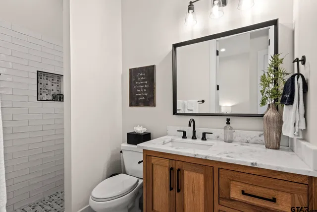 a bathroom with a granite countertop sink toilet a mirror and shower