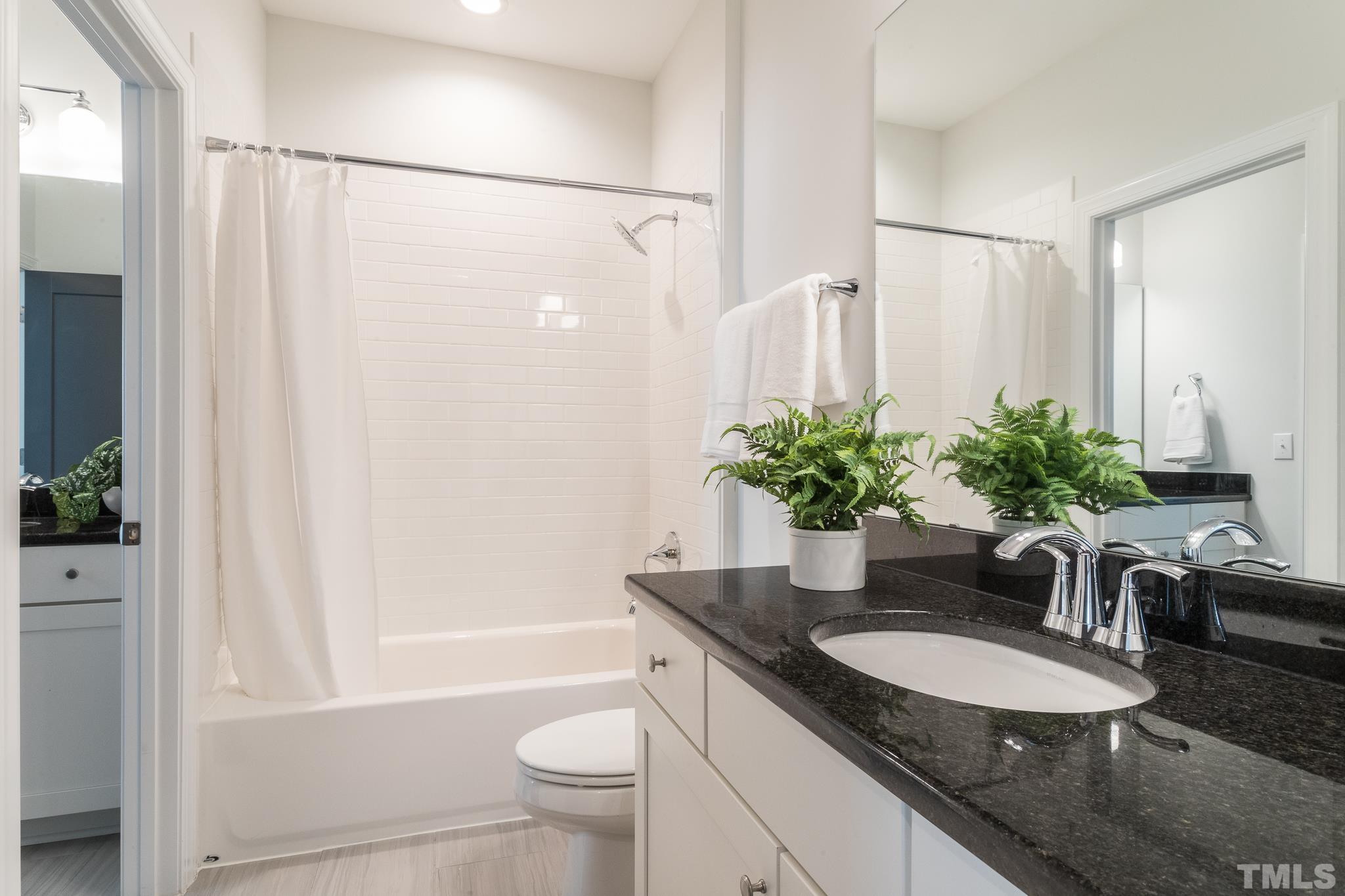 5601 Norcrest Street Raleigh, NC 27612 - Photo 26 of 41 a bathroom with a granite countertop sink a toilet a mirror and shower