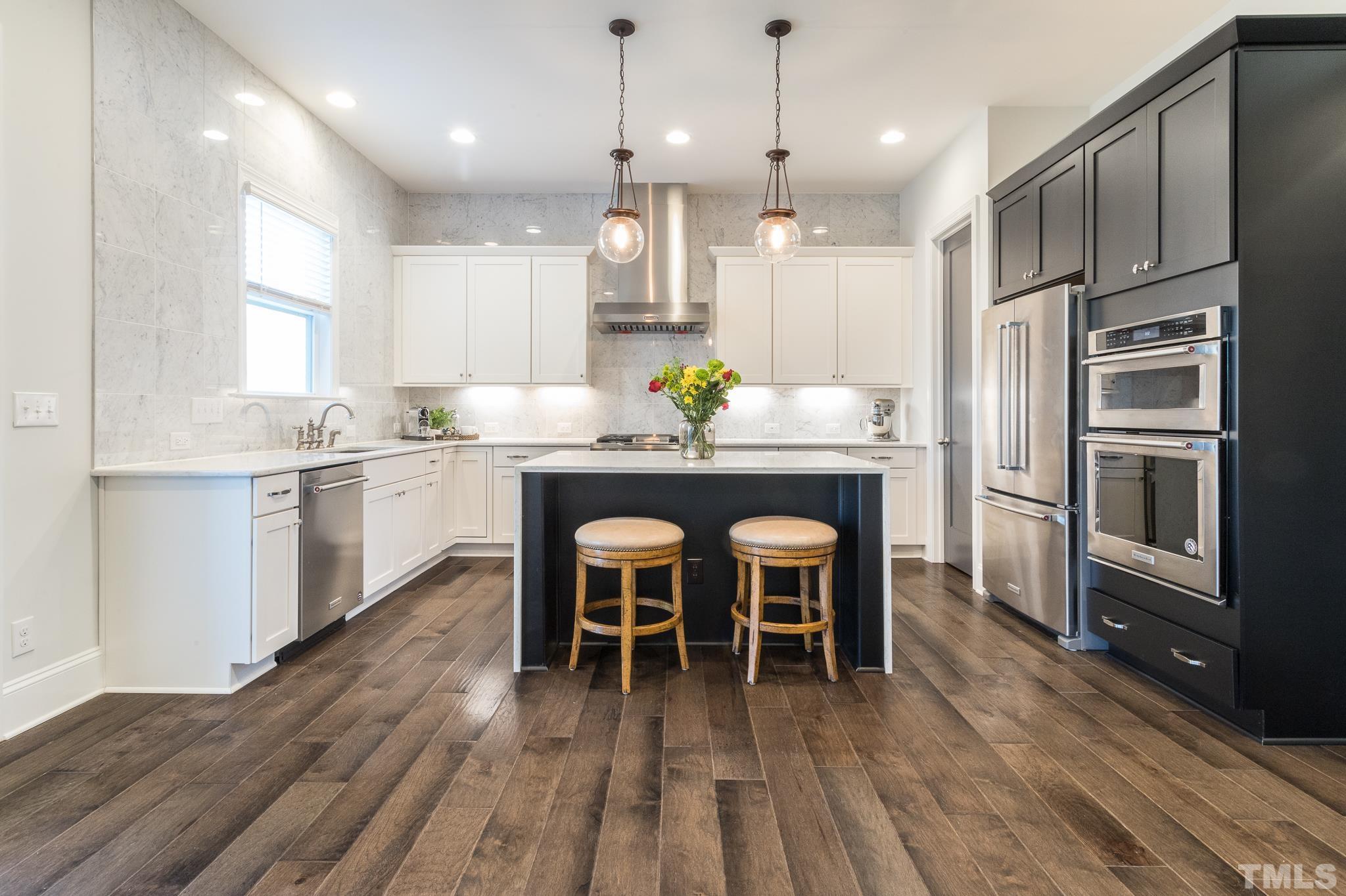 5601 Norcrest Street Raleigh, NC 27612 - Photo 9 of 41 a kitchen with stainless steel appliances a dining table chairs refrigerator and microwave