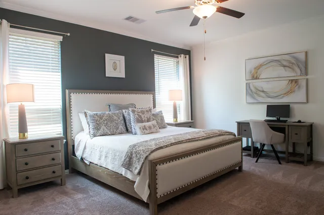 a bedroom with a bed a chandelier and a dresser