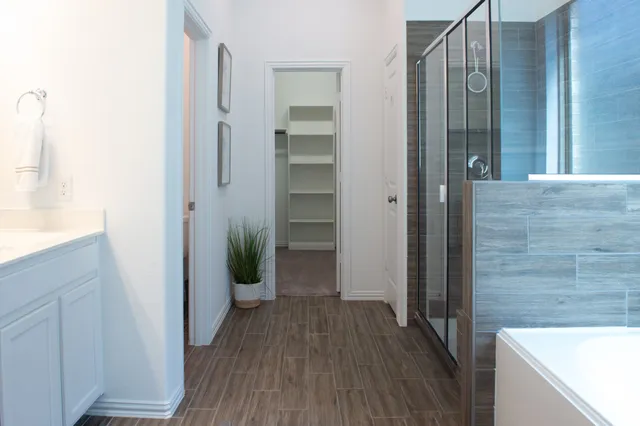 a view of a hallway with wooden floor and a bathroom