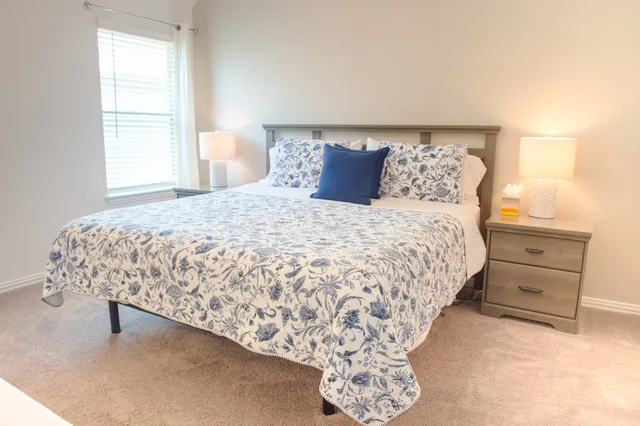 a bed sitting in a bedroom next to a window with dresser