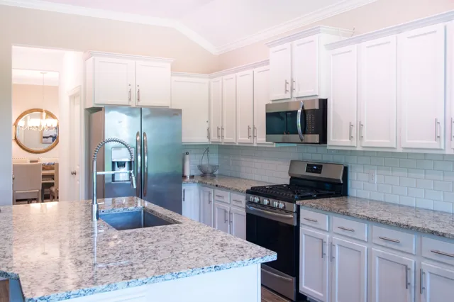 a kitchen with stainless steel appliances granite countertop a stove a microwave a sink and cabinets