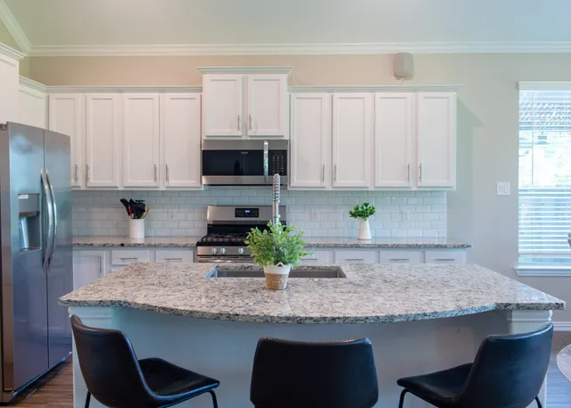 a kitchen with granite countertop white cabinets and stainless steel appliances
