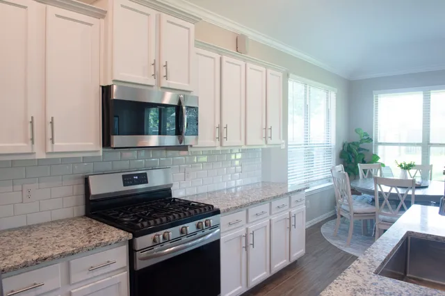 a kitchen with stainless steel appliances granite countertop a stove a sink and a microwave