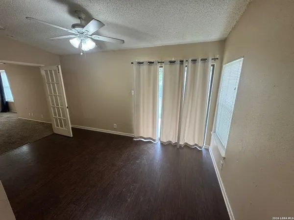 an empty room with wooden floor and fan