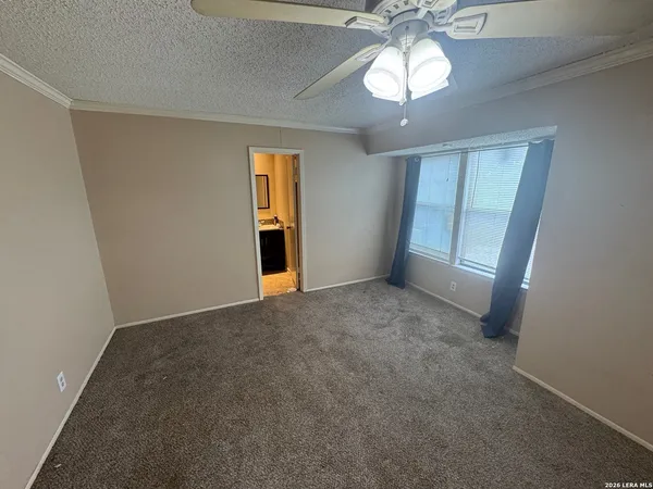 an empty room with a chandelier fan and windows