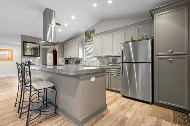 a kitchen with stainless steel appliances granite countertop a refrigerator a stove a sink a dining table and chairs