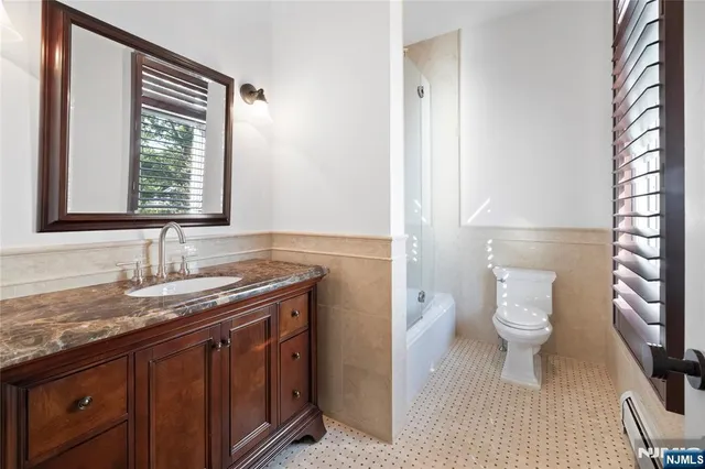 a bathroom with a granite countertop sink toilet and mirror