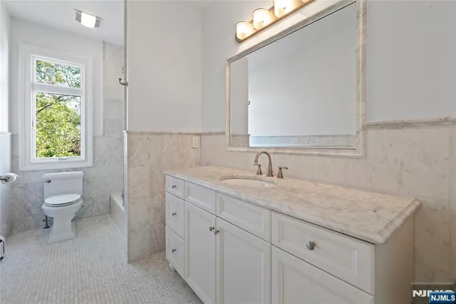 a bathroom with a granite countertop toilet a sink and a mirror