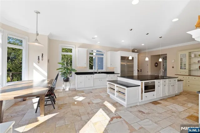 a kitchen with stainless steel appliances kitchen island granite countertop a stove and white cabinets