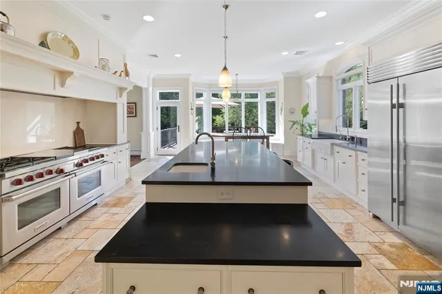 a kitchen with stainless steel appliances granite countertop a sink a stove and a refrigerator
