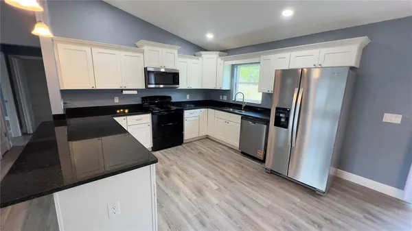 a kitchen with stainless steel appliances granite countertop a refrigerator a stove top oven a sink and dishwasher