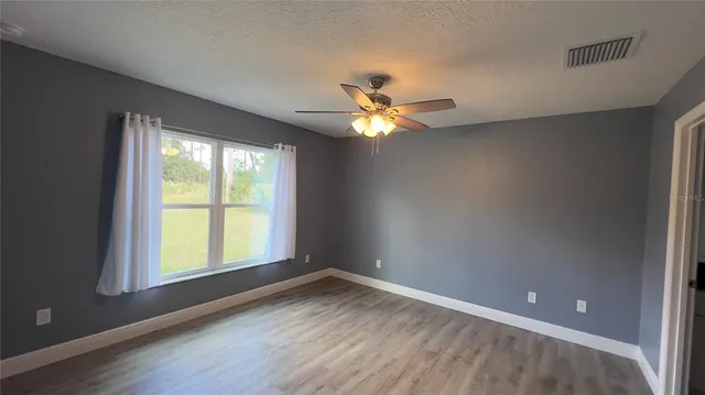 an empty room with a window and a fan