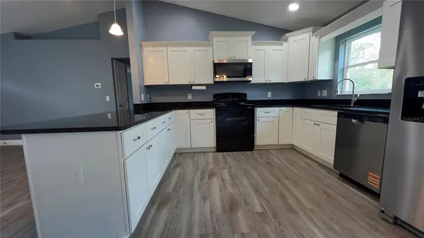 a kitchen with stainless steel appliances granite countertop a stove a sink and a microwave