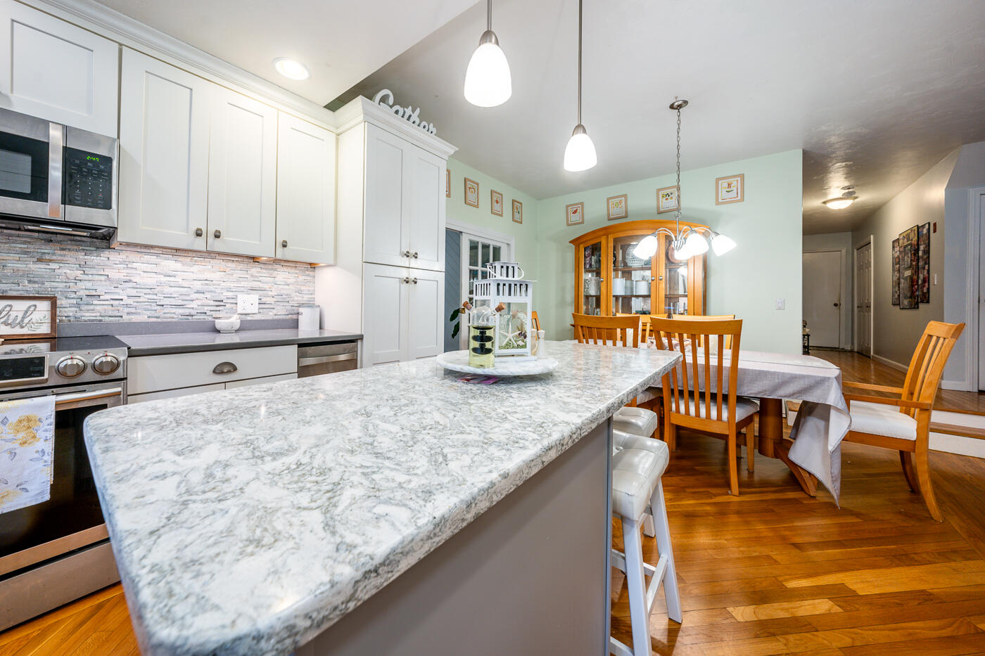 23 Redwood Circle Mashpee, MA 02649 - Photo 14 of 40 a kitchen with stainless steel appliances granite countertop a stove a sink a dining table and chairs with wooden floor