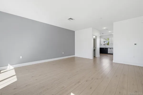 a view of an empty room with wooden floor and windows